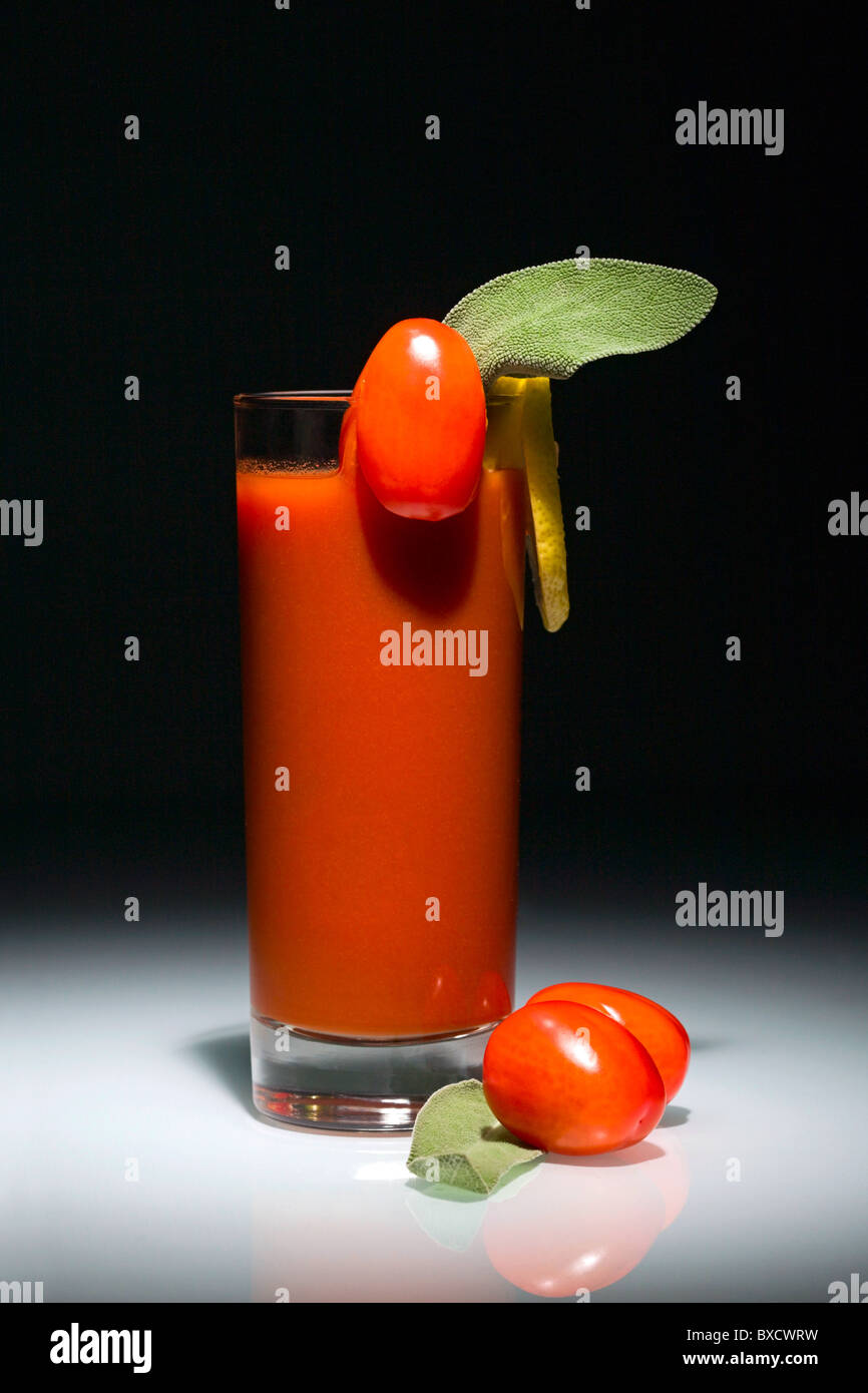 Bloody Mary cocktail in vetro con pomodori e fetta di limone isolati su sfondo nero Foto Stock