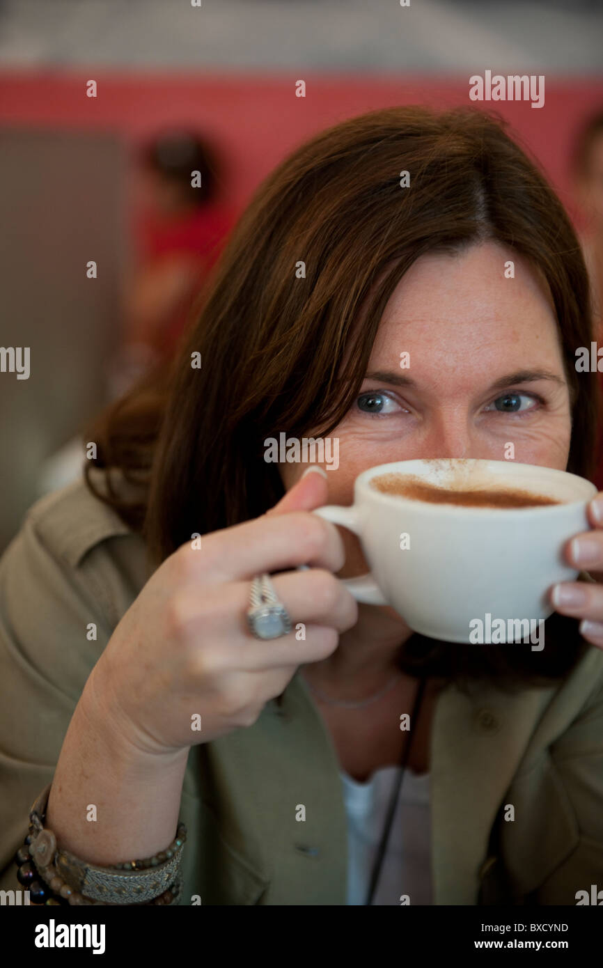 Donna spiata su una tazza piena di caffè latte Foto Stock