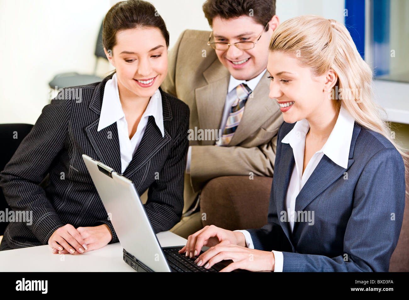 Ritratto di tre giovani specialisti guardando un monitor di computer portatile Foto Stock