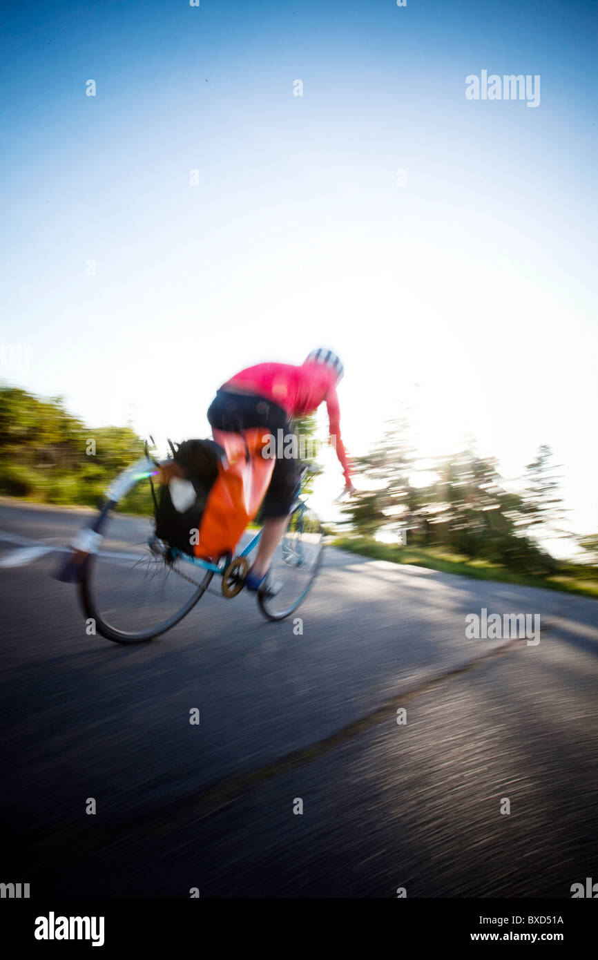 Una giovane donna vanno in bicicletta intorno a un parco al tramonto. Foto Stock