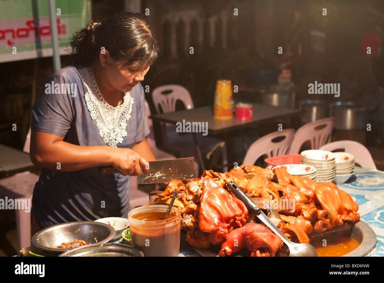 Donna birmana il taglio di pezzi di maiale Foto Stock