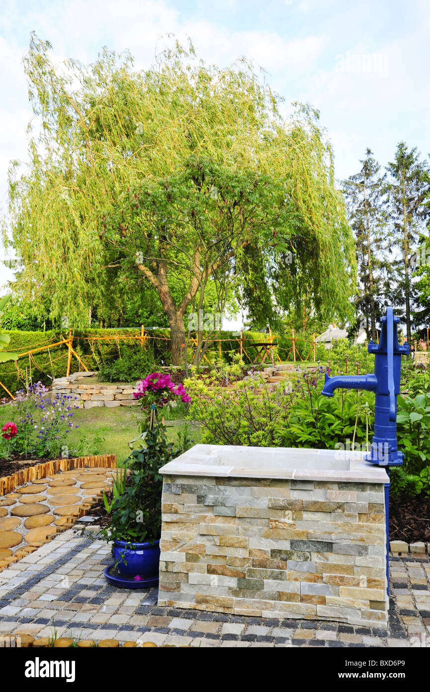 Natura giardino con muro di pietra e terrazza in legno Foto Stock