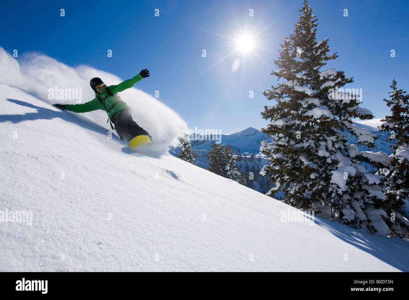 Uno snowboarder rendendo alcune nuove tracce in una giornata di sole in Utah. Foto Stock