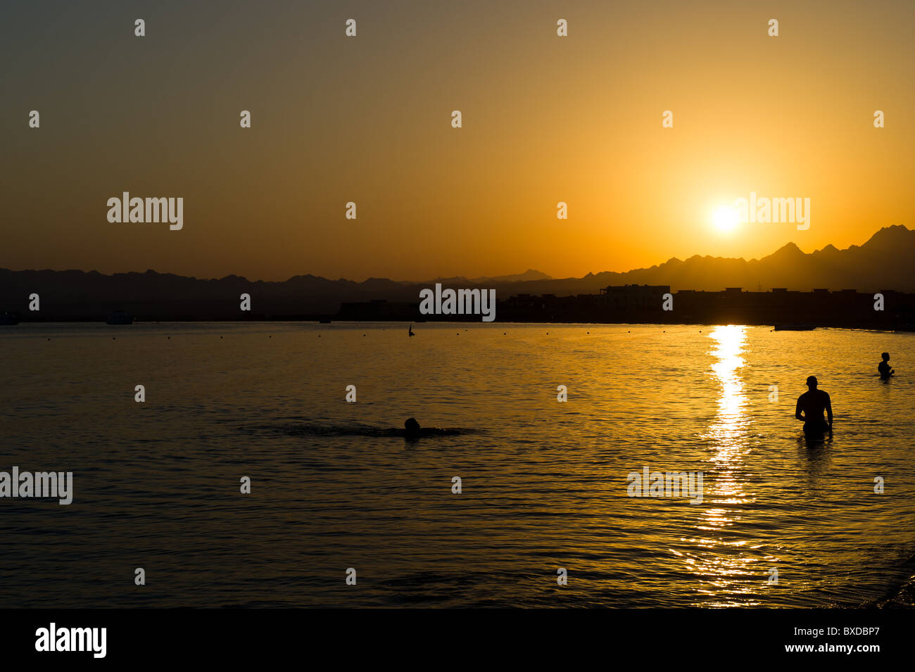 La gente di nuoto nel mare rosso al tramonto a Soma Bay nei pressi di Safaga e Hurghada in Egitto Foto Stock