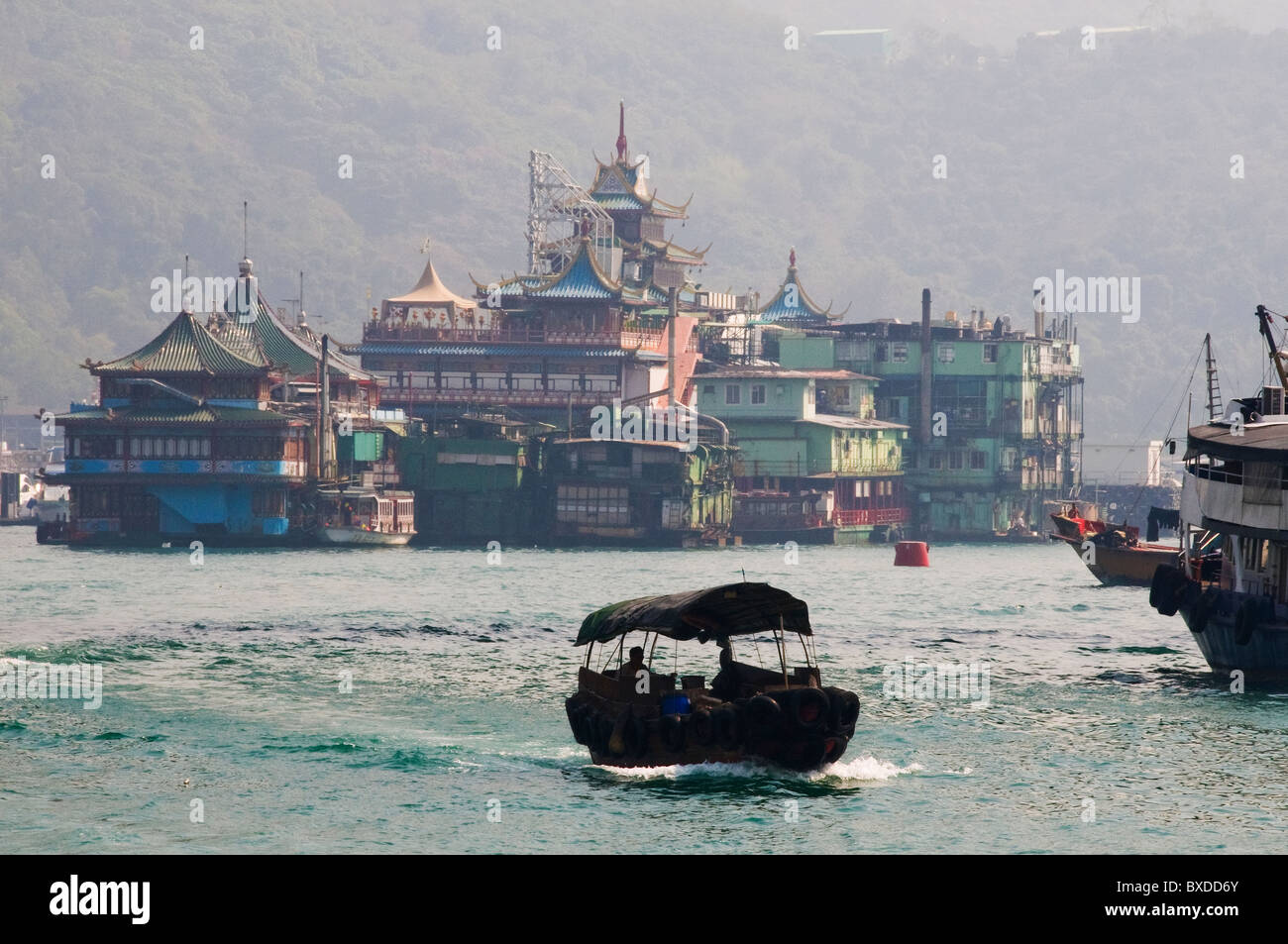 Unica barca bum in viaggio lungo la via navigabile in Hong Kong Cina con gamberoni ristorante in background Foto Stock