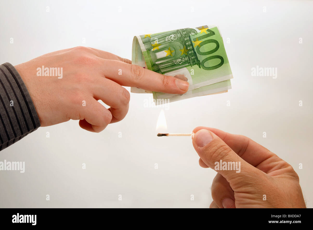 Mano maschio con un match sta tentando di masterizzare le banconote in euro Foto Stock