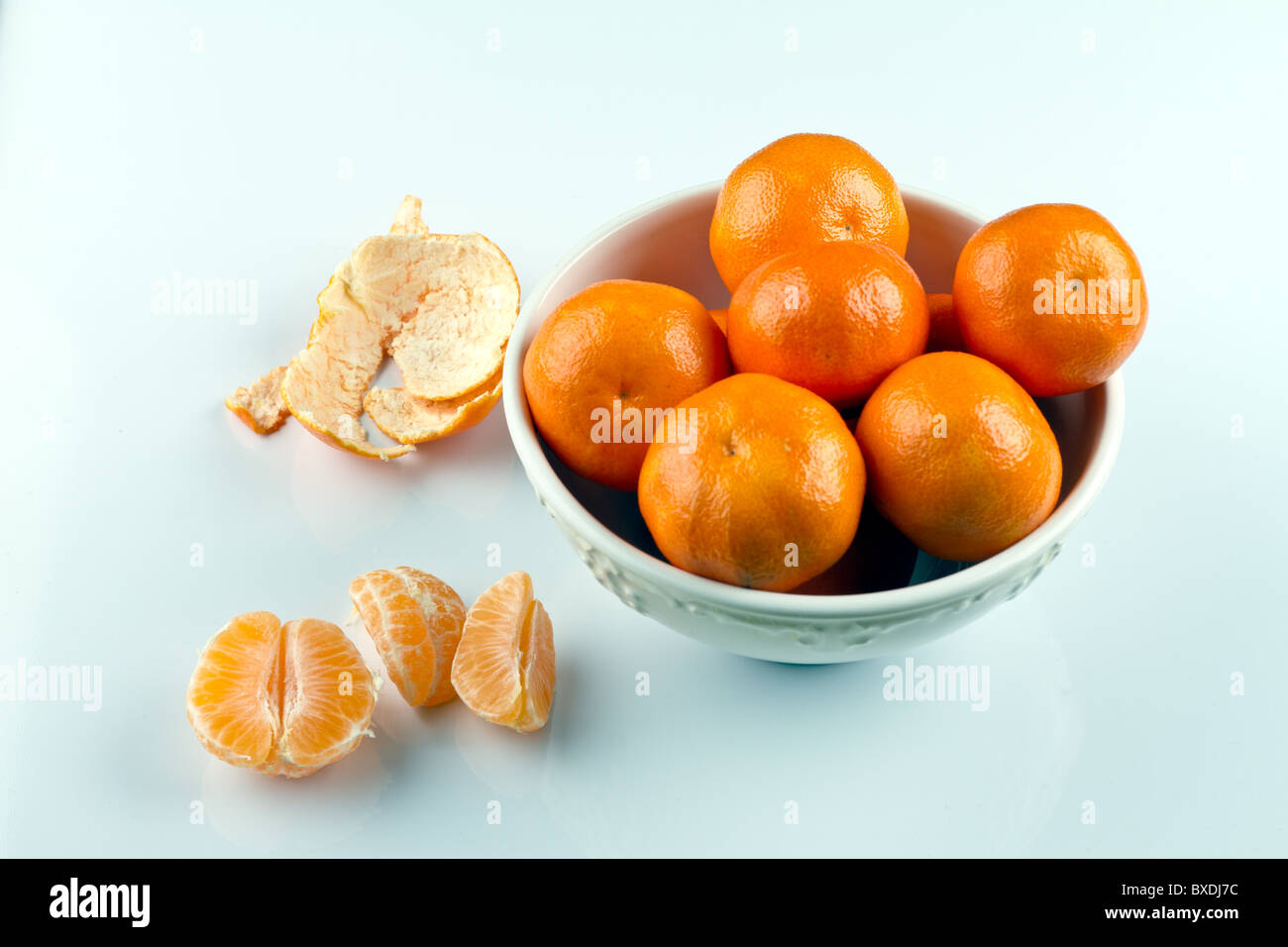 Sbucciate le clementine e clementine in vaschetta bianca sulla superficie bianca Foto Stock