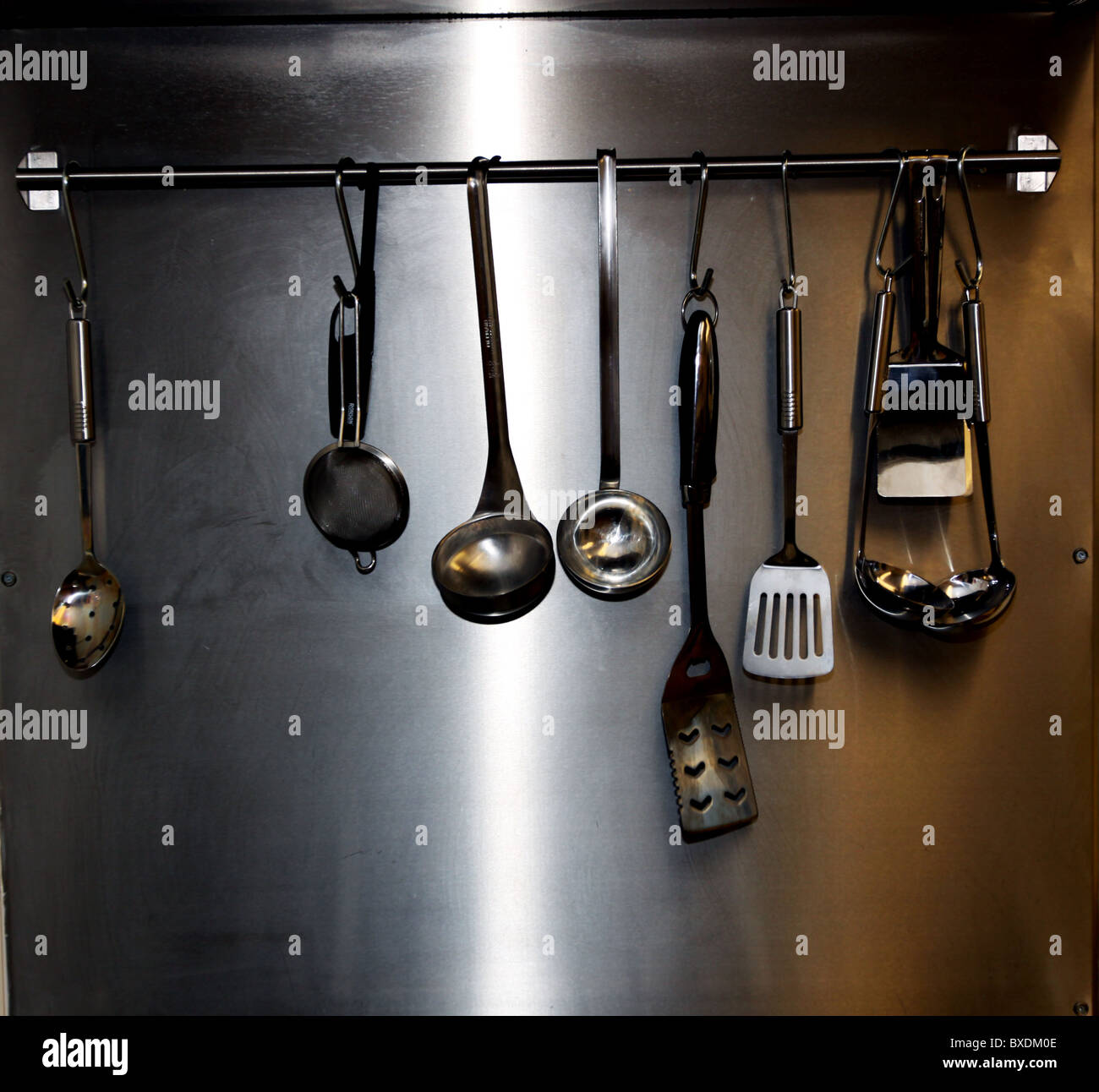 Utensili da cucina appeso su rotaia in cucina commerciale Foto Stock