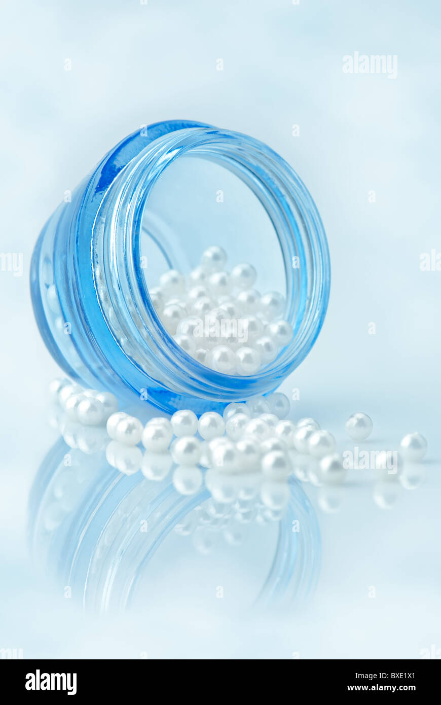 Concetto di bellezza. Contenitore per cosmetici pieno di perle naturali su sky imitando lo sfondo. Tinta blu, la profondità di campo Foto Stock