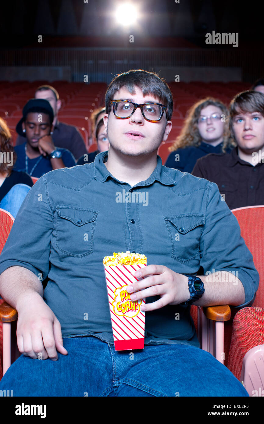 Uomo caucasico mangiare popcorn in movie theater Foto Stock