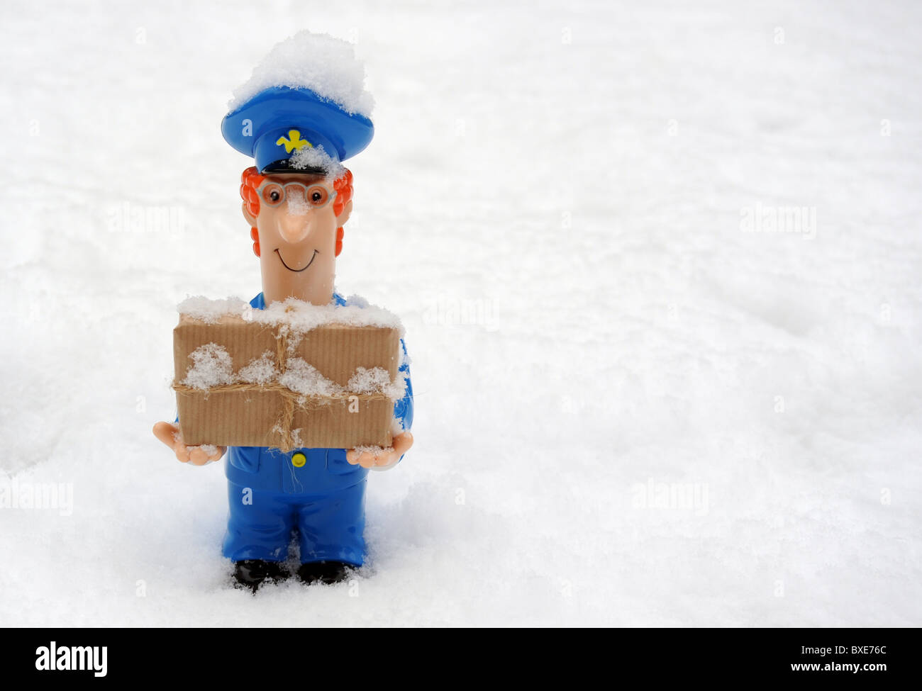 Portalettere figura con pacco in presenza di neve ghiacciata condizioni meteo RI POST OFFICE INVERNO CONSEGNE RITARDI ETC UK SERVIZIO POSTALE Foto Stock