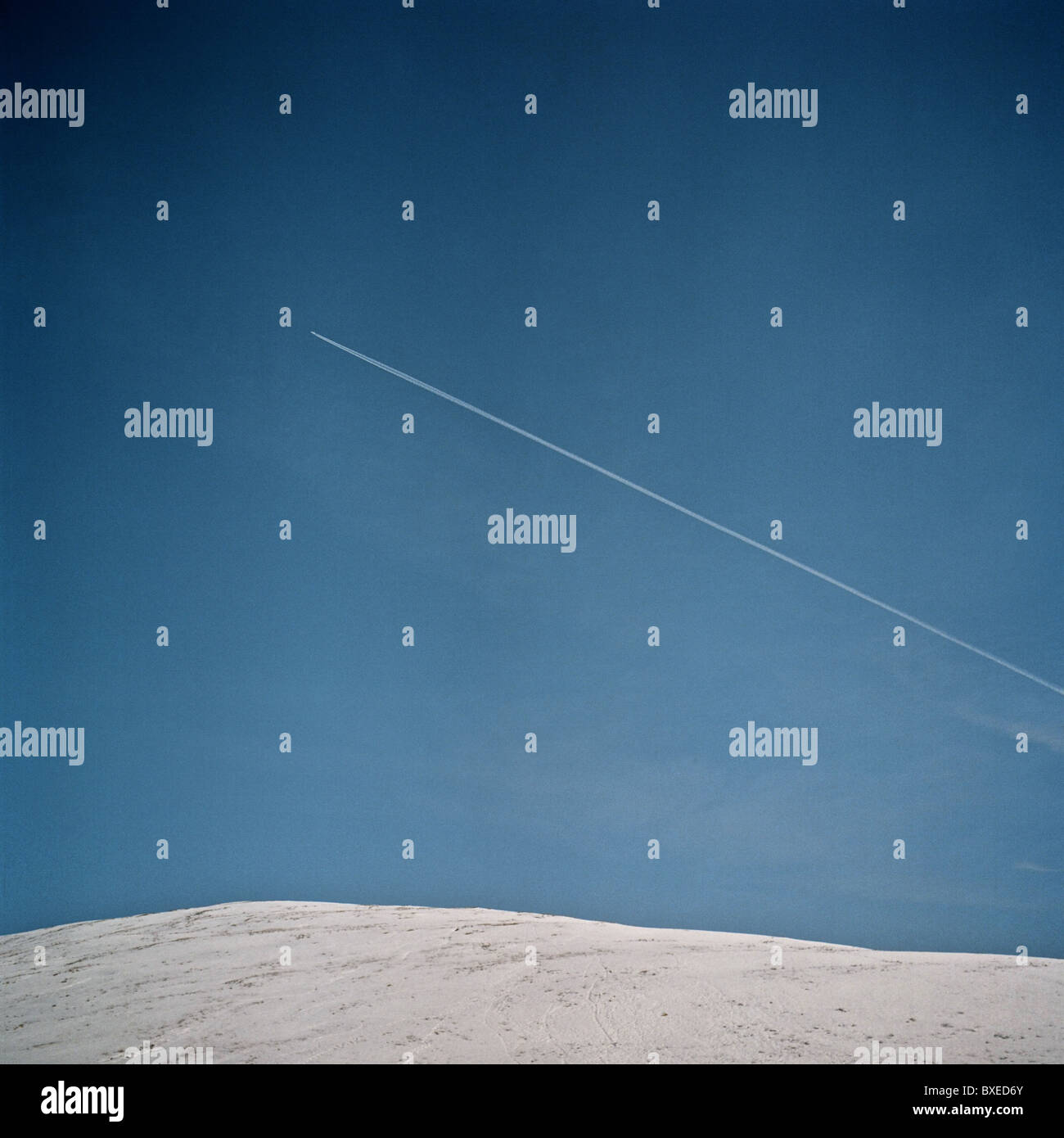 Paesaggio minimalista che mostra un percorso di vapore aereo attraverso un cielo blu sopra il nevoso Campsie Fells. Foto Stock