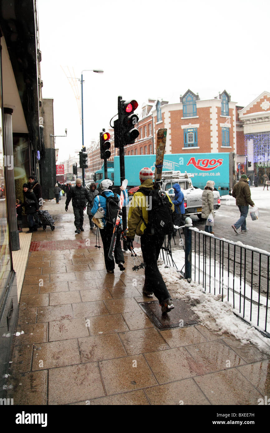 Due persone a piedi fino a Putney High Street con gli sci. Londra Foto Stock