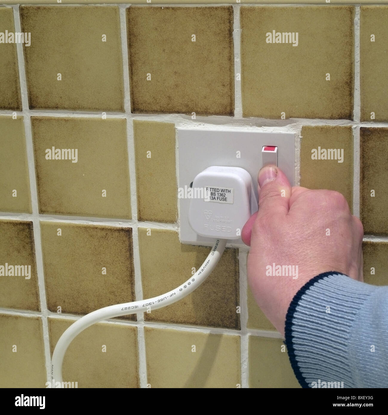 Uomo caucasico accensione/spegnimento alimentazione elettrica con una presa a muro con tre pin connettore con fusibile collegato, REGNO UNITO Modello rilasciato Foto Stock