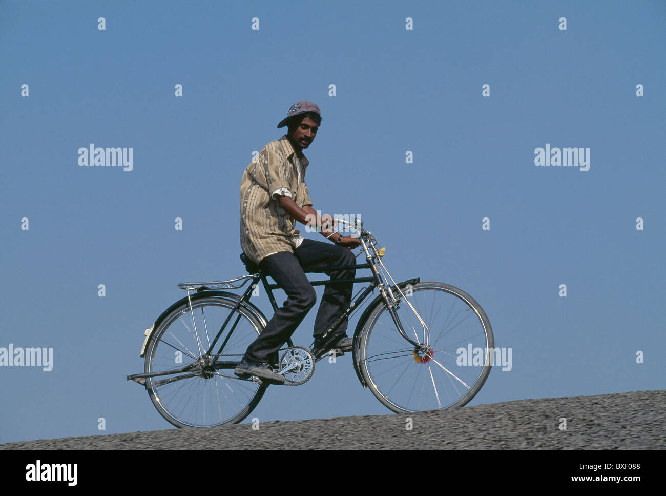 Un lavoratore corse in bicicletta lungo un controllo di inondazione berm al 4.8 km Jamuna Bridge project. Foto Stock