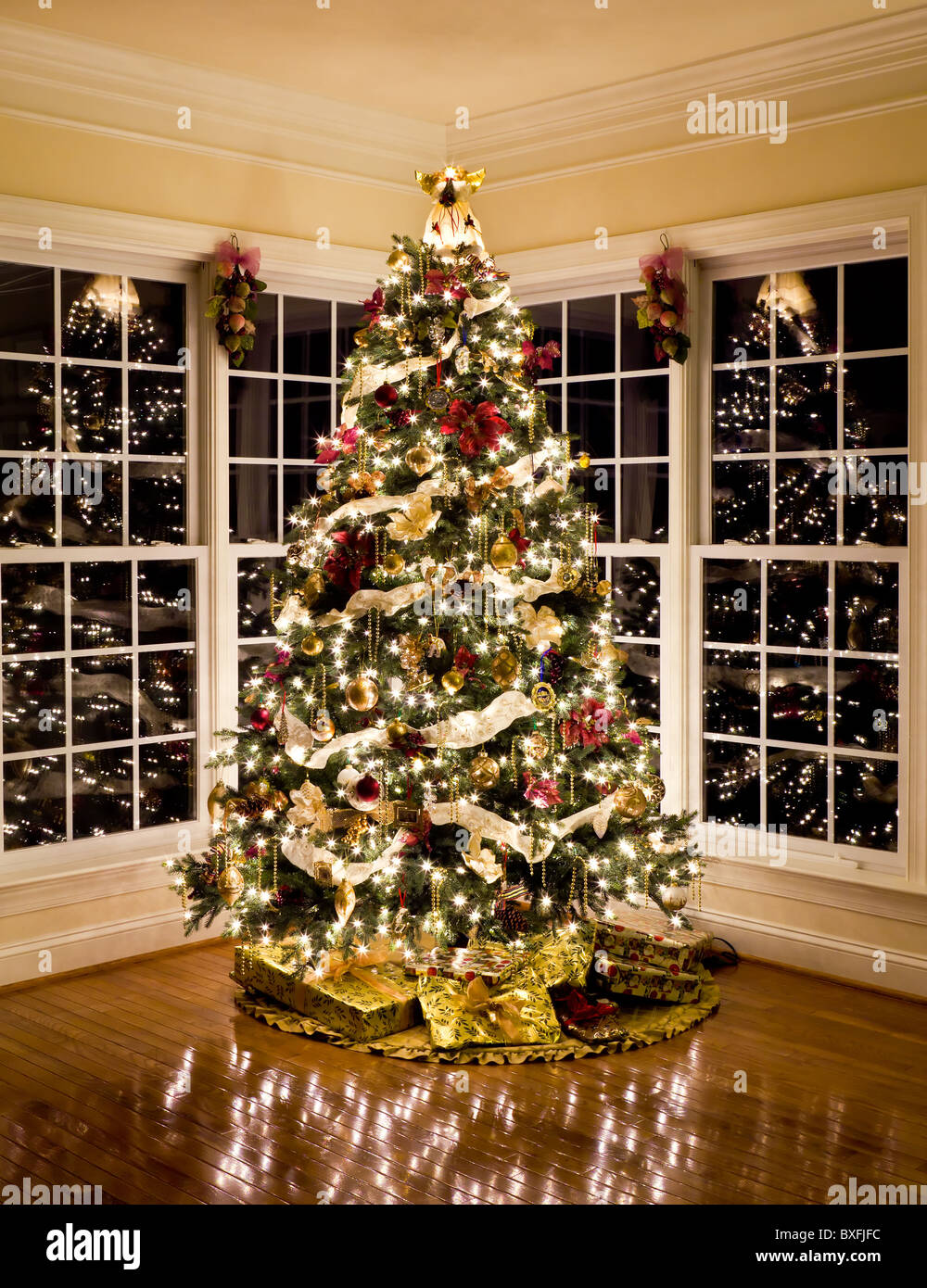 Albero di Natale con regali e luci che riflettono in windows intorno all'albero nel salotto di casa Foto Stock