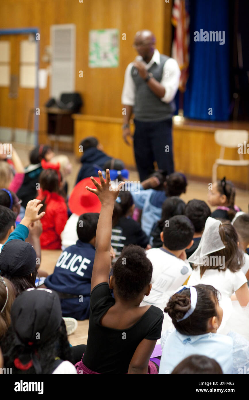 Terza classe student alza la mano per chiedere domanda durante i bambini è autore Derrick Barnes' presentazione ad un gruppo scolastico Foto Stock