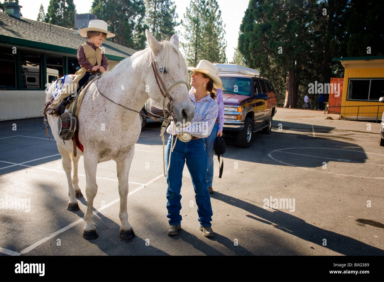 Little cowboy a cavallo con sua madre a guardare Foto Stock