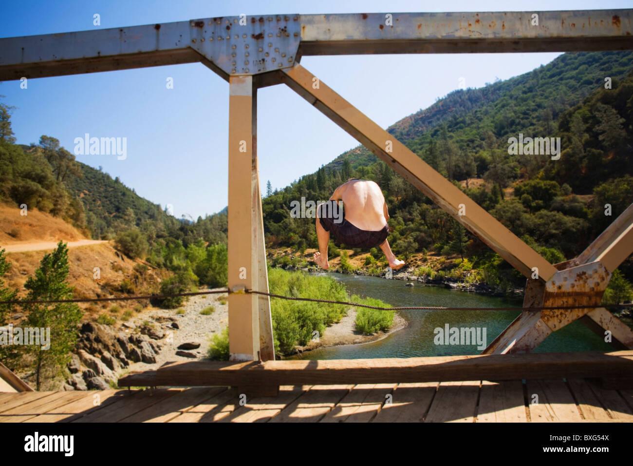 Uomo caucasico saltando nel fiume dal ponte Foto Stock