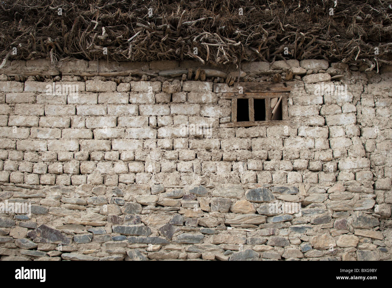 Una casa di pietra nella parte interna dell'Himalaya in India. La gente del luogo raccogliere legna da ardere in estate e conservarla al di sopra della casa per il lungo inverno Foto Stock