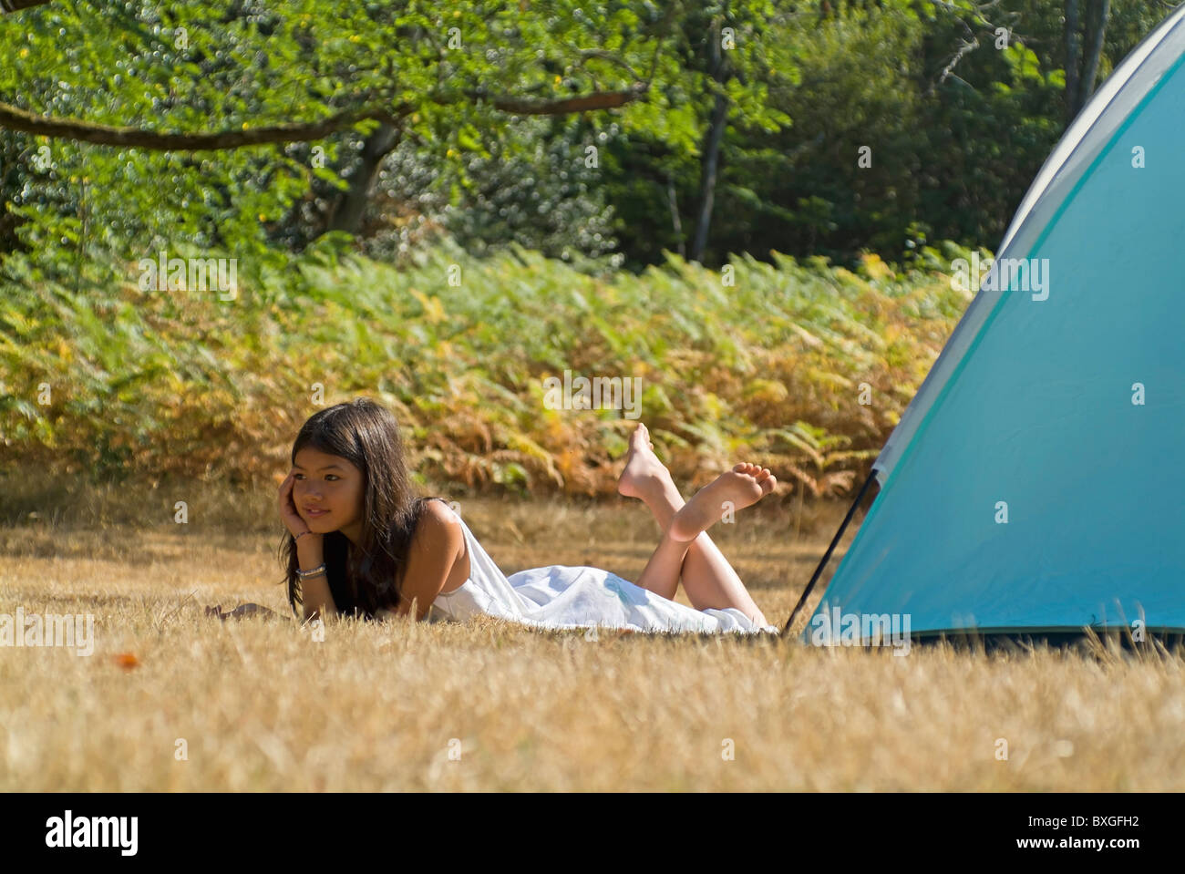 Vacanza in campeggio - ragazza giovane disteso accanto ad una tenda da campeggio nella foresta delle Landes, Aquitaine, Francia. Foto Stock