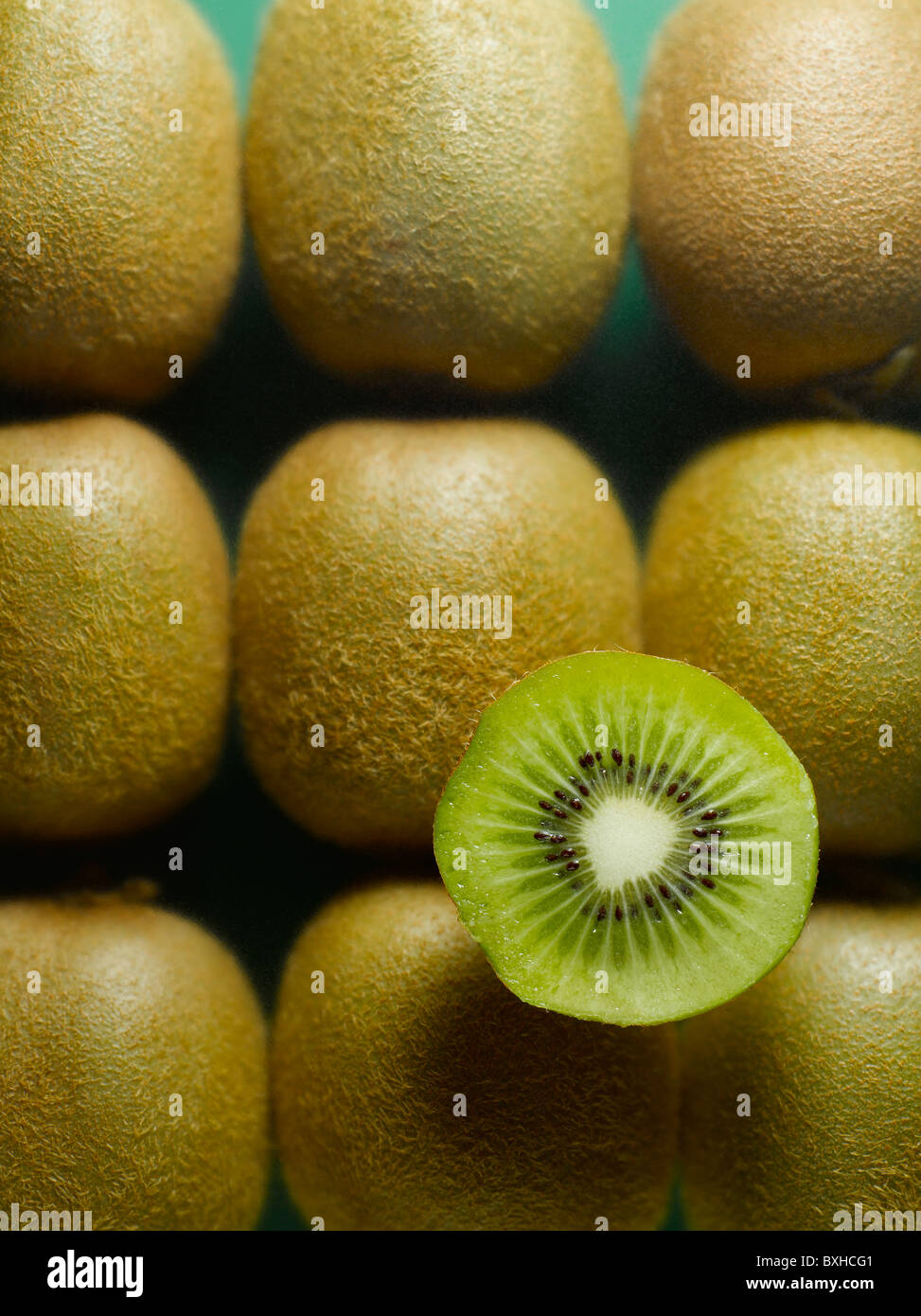 Tutto il kiwi con metà a fette kiwi su sfondo verde Foto Stock