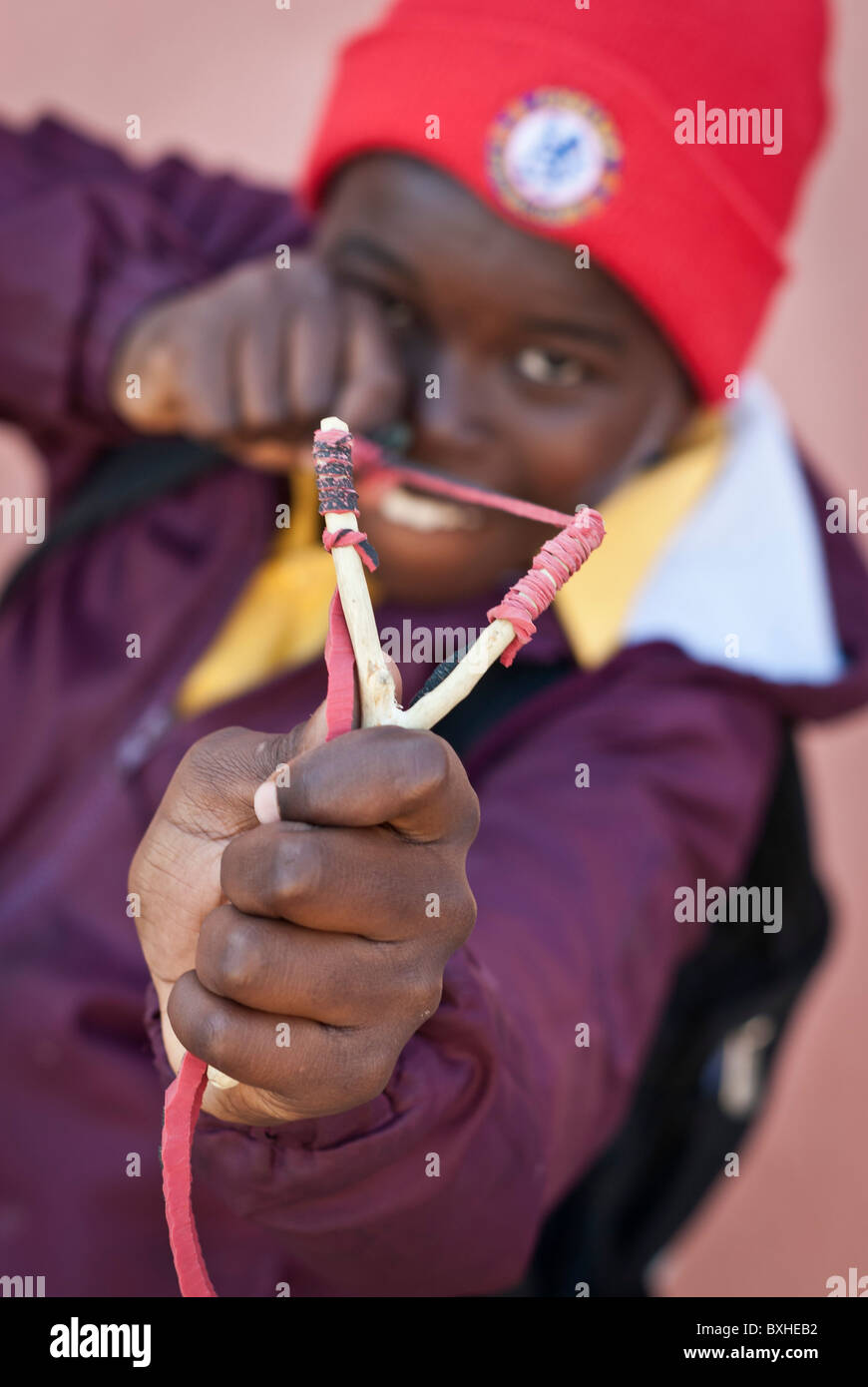 Ragazzo puntando alla telecamera con la sua fionda, Lüderitz, Namibia, Africa Foto Stock
