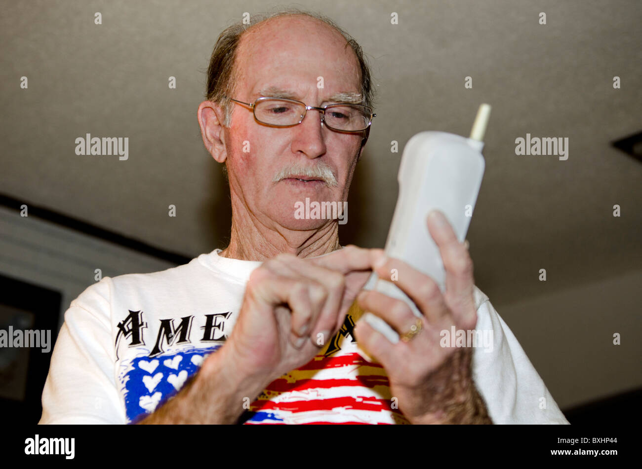 Un anziano uomo caucasico di porre una chiamata compone su un telefono cordless. Stati Uniti d'America. Foto Stock
