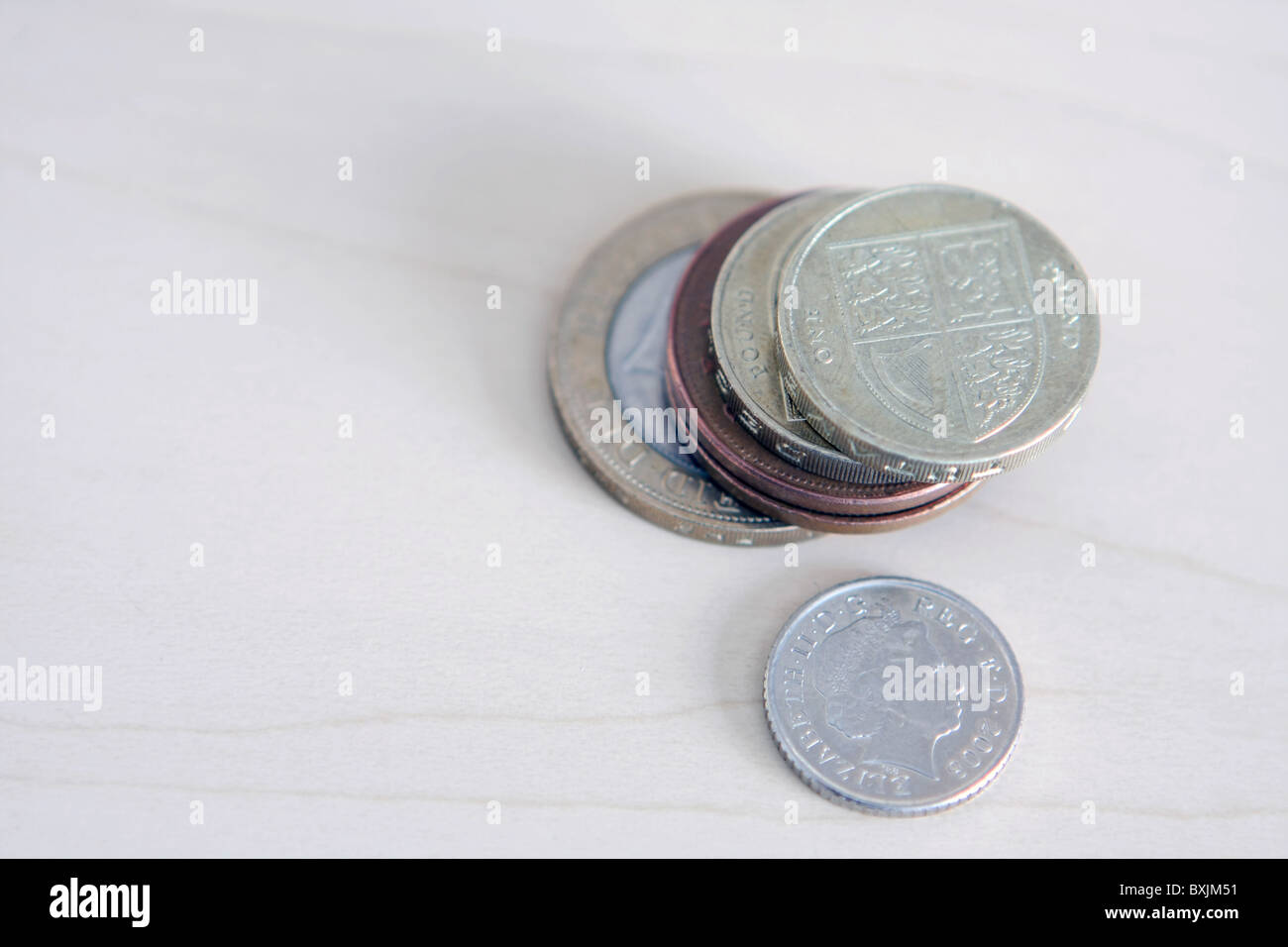 Una piccola pila di sterling monete, che include 2 sterline, £1 e 2p monete, accanto a un singolo 5p coin Foto Stock