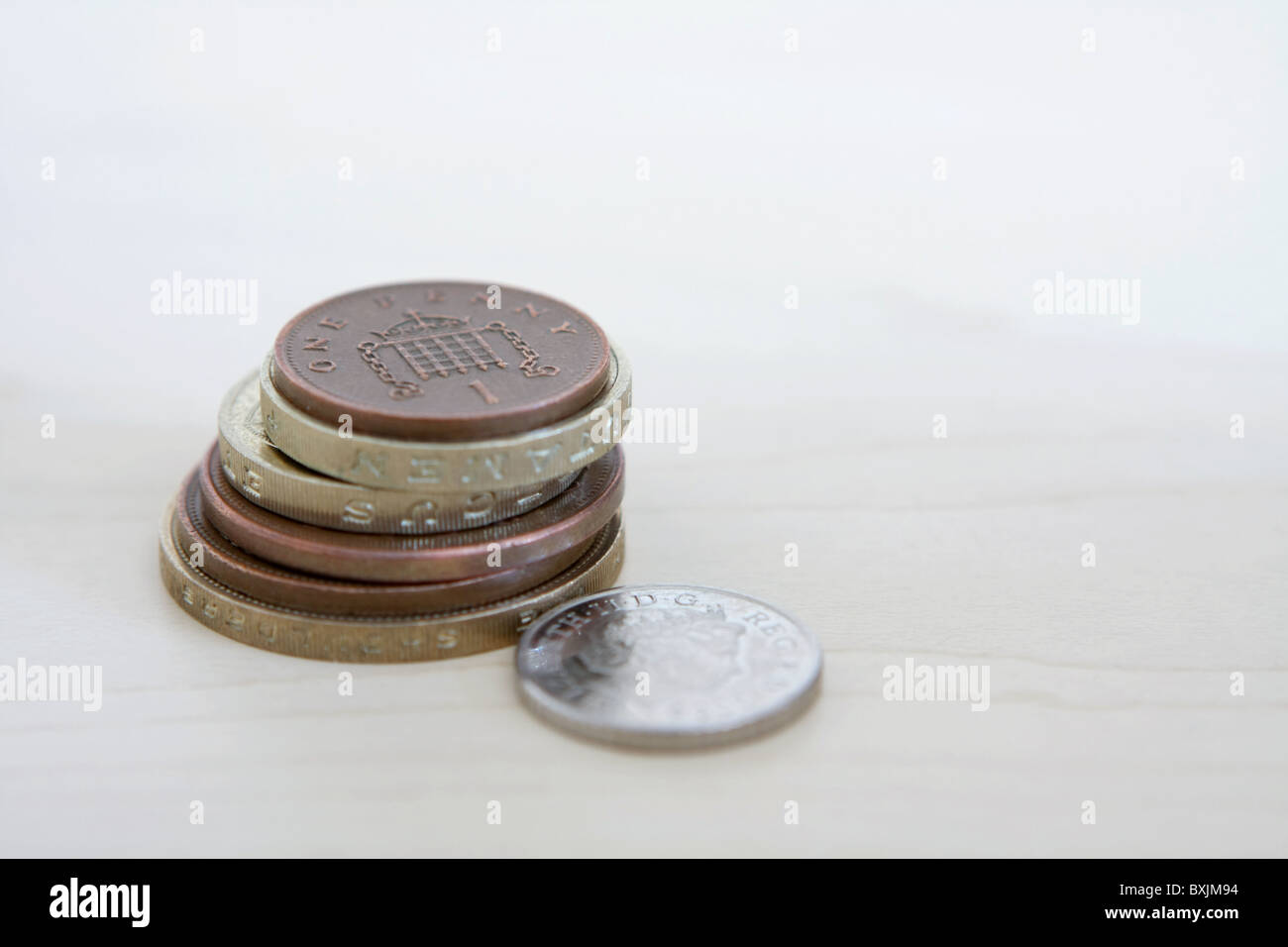 Un unico sterling 5p coin accanto ad una piccola pila di sterling monete, che include 2 sterline, £1, 2p e 1p delle monete in euro Foto Stock
