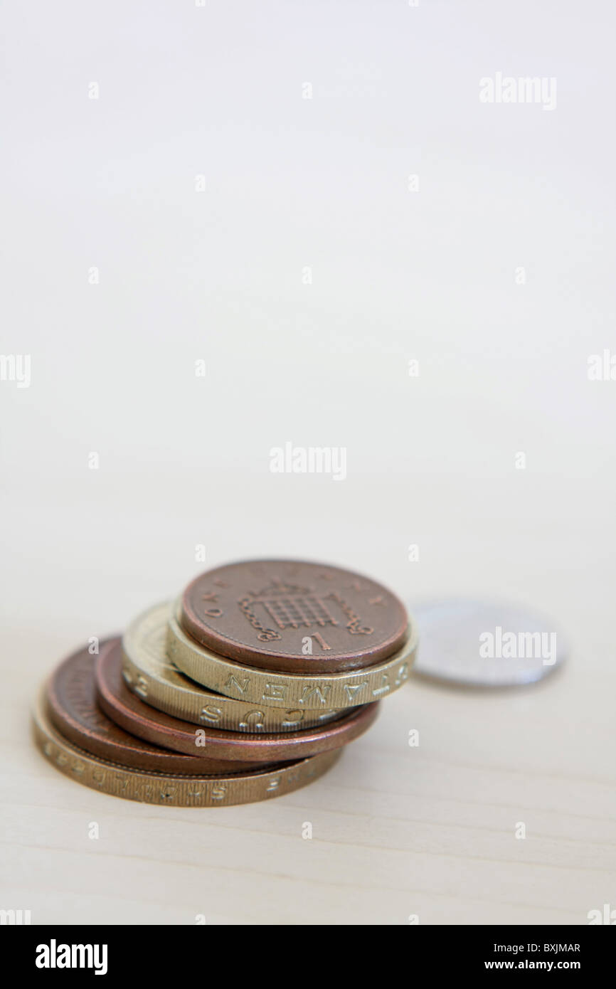 Un unico sterling, fuori fuoco 5p coin accanto ad una piccola pila di sterling monete, che include 2 sterline, £1, 2p e 1p delle monete in euro Foto Stock