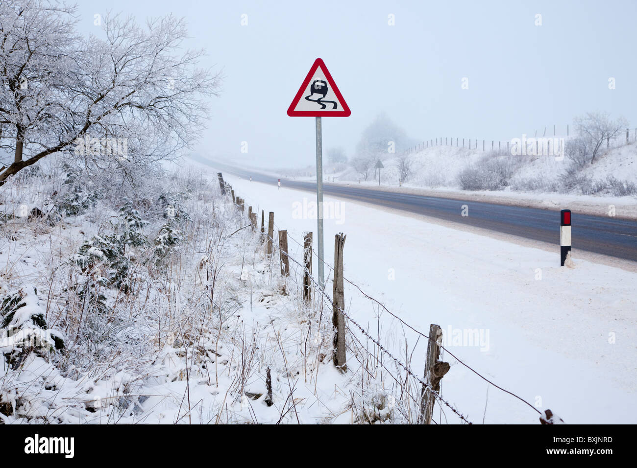 Strada invernale con il congelamento nebbia, neve e segno di avvertimento, vicino Floak sulla strada di Glasgow, Ayrshire, in Scozia Foto Stock