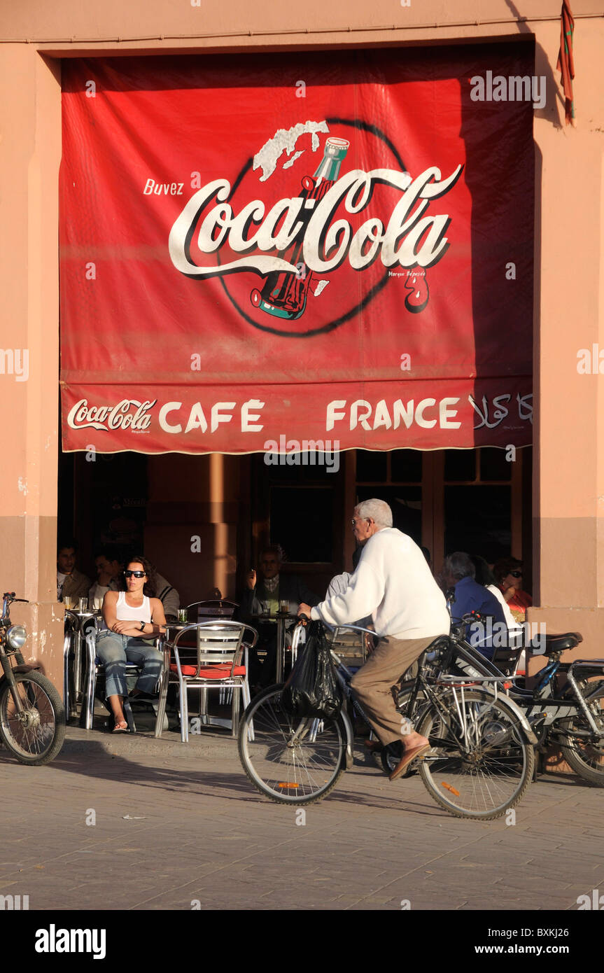 Ciclista passando il Cafe de france terrazza a occupato Djemaa el Fna luogo di incontro di Marrakech Foto Stock