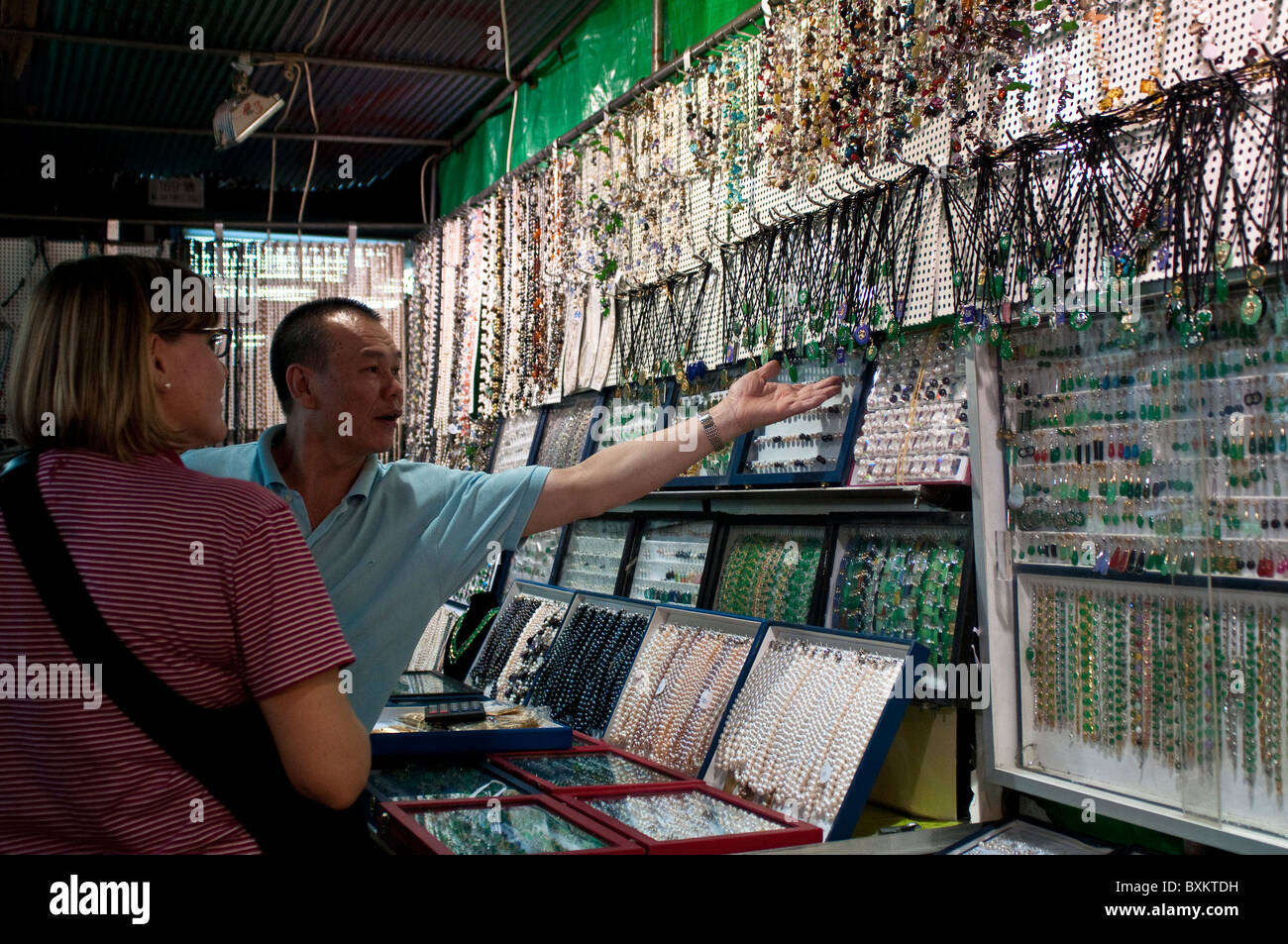 Il venditore che mostra gioielli di shopper, il Mercato Notturno di Temple Street,Yau Ma Tei, Kowloon, Hong Kong, Cina Foto Stock