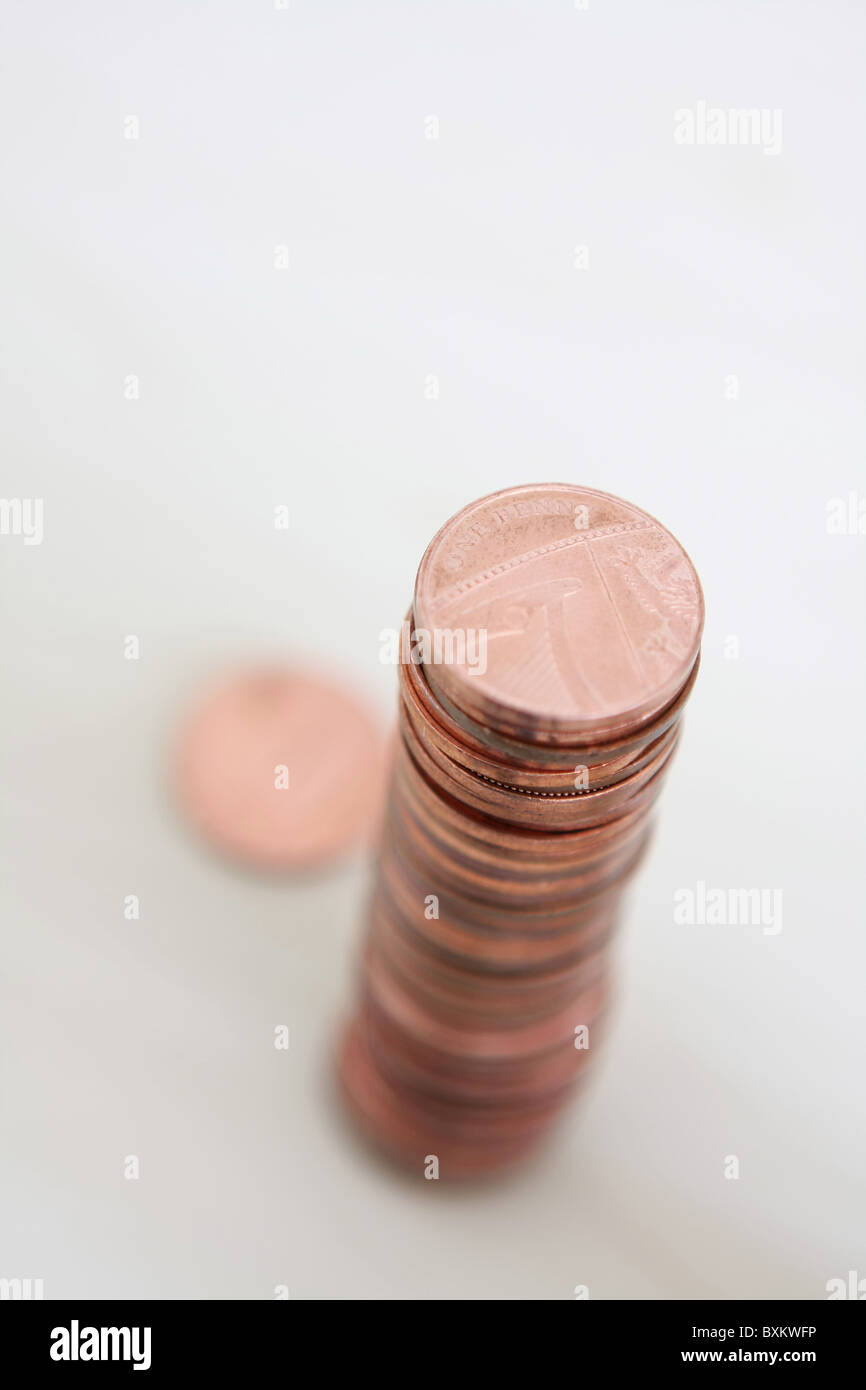 Una pila di sterling 1p monete visto da sopra con un fuori fuoco coin allentato dalla pila Foto Stock