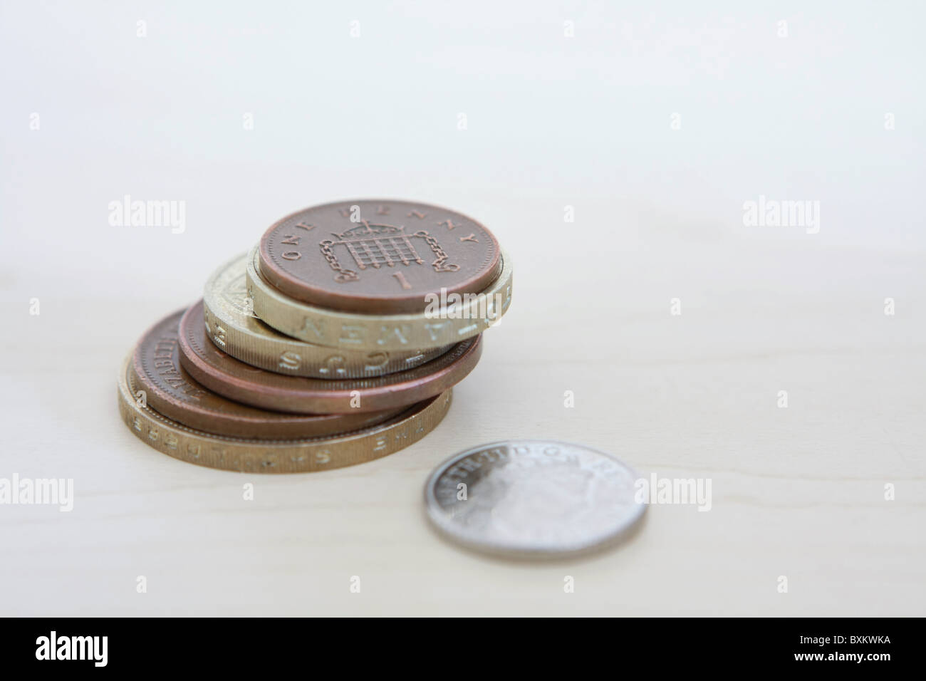 Una sterlina 5p coin accanto a una pila di denominazione diversa sterling monete Foto Stock