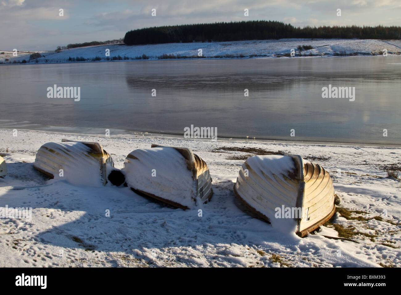 Inverno freddo paesaggio di neve di sgombrato upturned stock barche di pesca, lago di riserva di fiume United Utilities. Valle di Bowland, Lancashire, Regno Unito Foto Stock