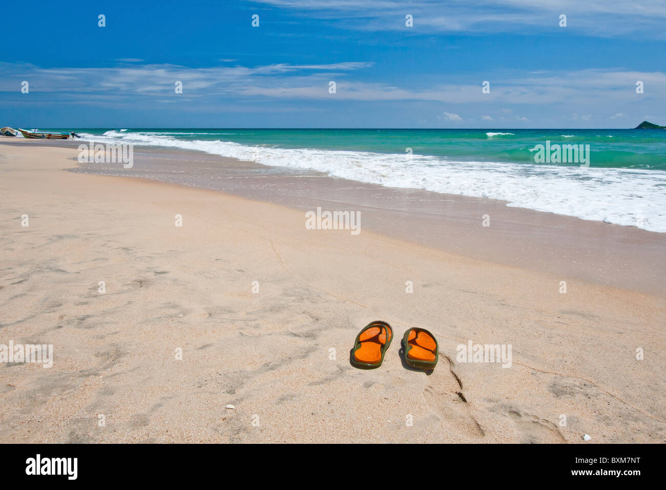 Paio di pantofole su una solitaria spiaggia di Nilaveli, Trincomalee, Sri Lanka East Coast, Pigeon Island in distanza. Foto Stock