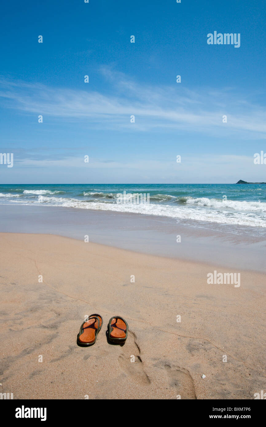 Paio di pantofole su una solitaria spiaggia di Nilaveli, Trincomalee, Sri Lanka East Coast, Pigeon Island in distanza. Foto Stock