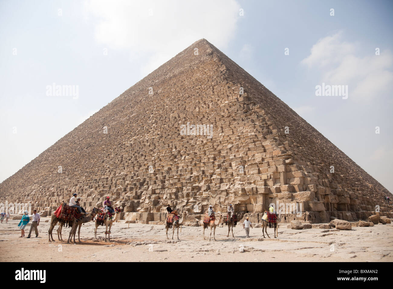 A dorso di cammello venditori escursione sulla schiena del cammello, i clienti in attesa attorno al grande piramide. Foto Stock