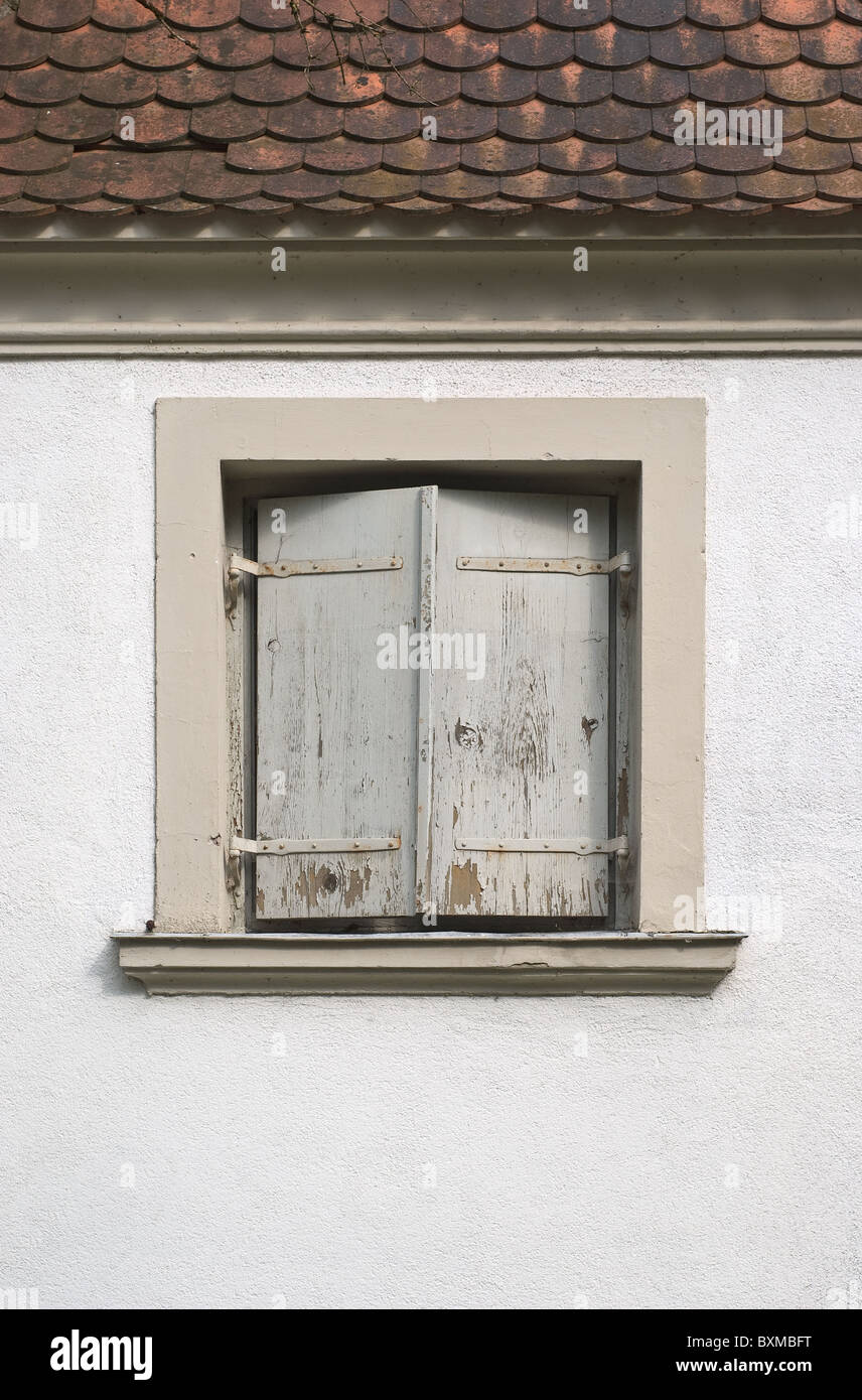 Invecchiamento e Weathered finestra con tapparelle su una casa in Germania Foto Stock