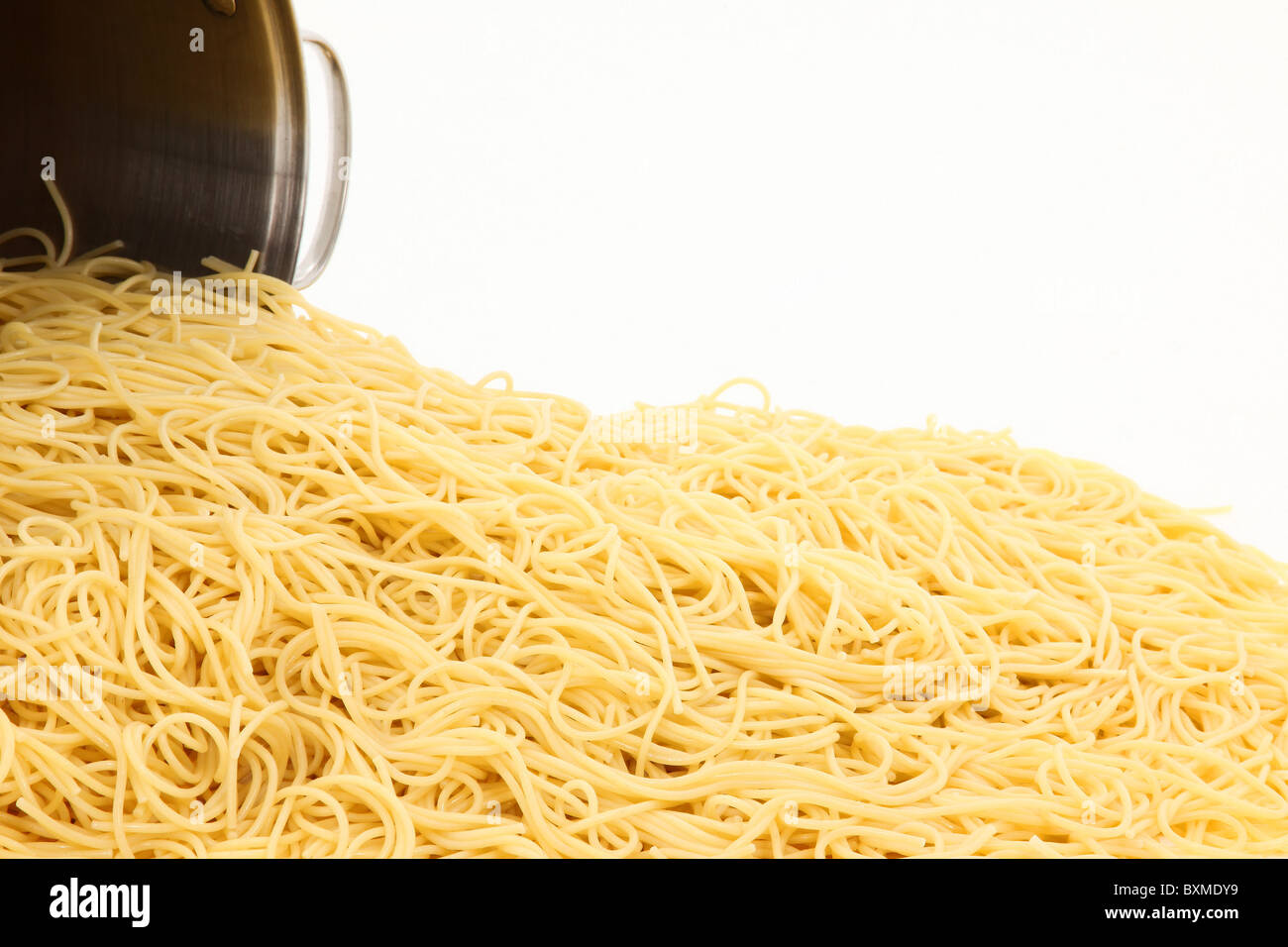 Una grande pentola di spaghetti noodles plain versato su sfondo bianco. Foto Stock