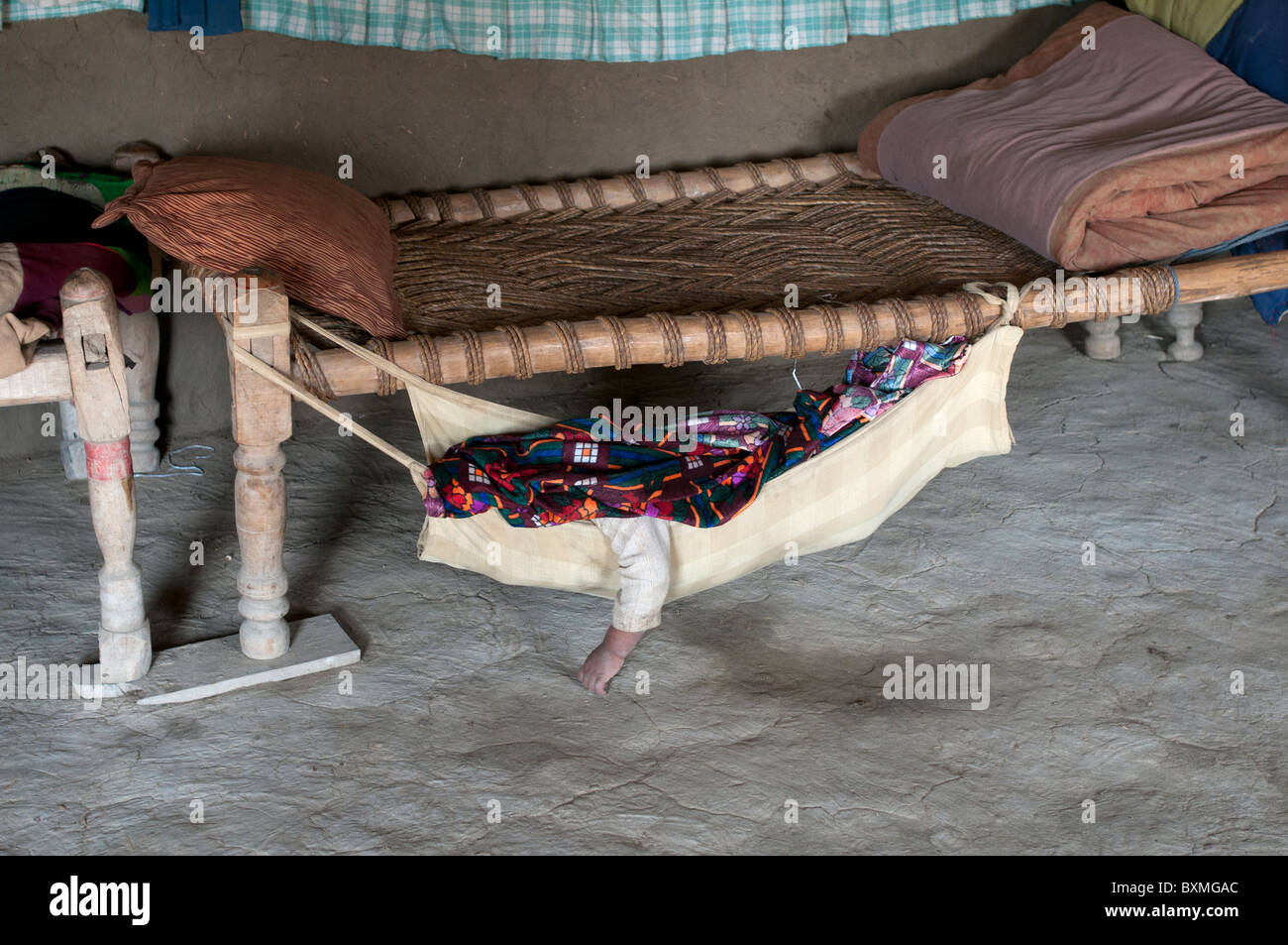 Il Pakistan dopo il diluvio.Kheshgi camp per i rifugiati afghani. Il bambino dorme in un amaca infilate sotto un letto di corda. Foto Stock