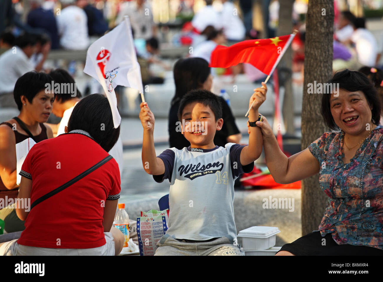 Bambino cinese sventolando bandiere all'interno Olympic Stadium Complex, Pechino, Cina Foto Stock
