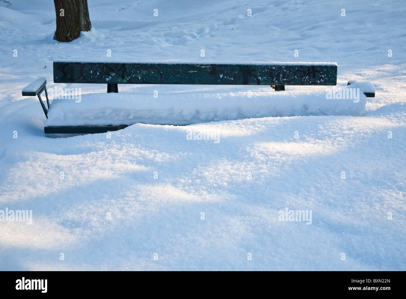 Una panchina nel parco coperto di neve profonda Foto Stock