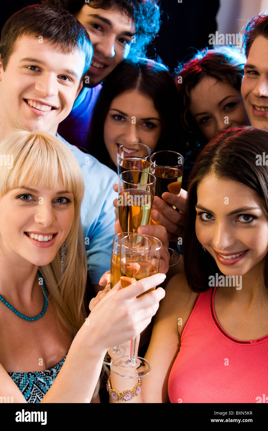 Immagine di sorridere amici azienda bevande alcoliche e guardando la fotocamera Foto Stock