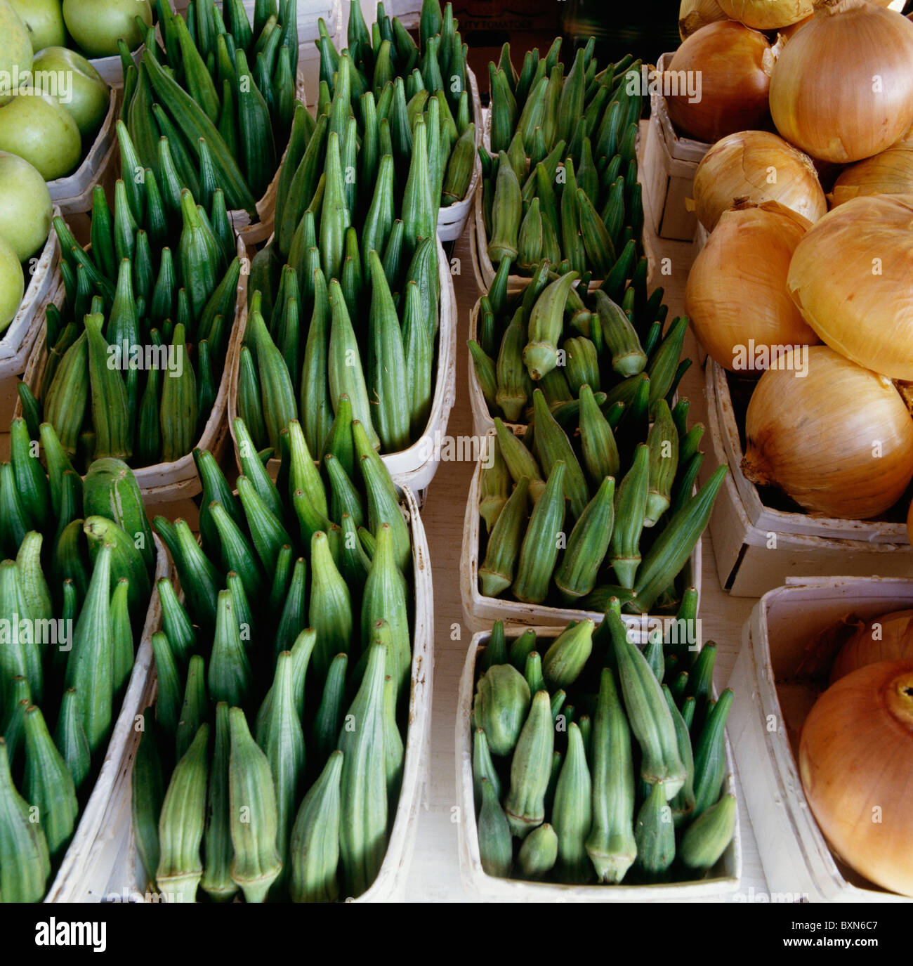 Vassoi di okra circondata con le cipolle e le mele a HABERSHAM STAND VEGETALI HAVERSHAM COUNTY, GEORGIA Foto Stock