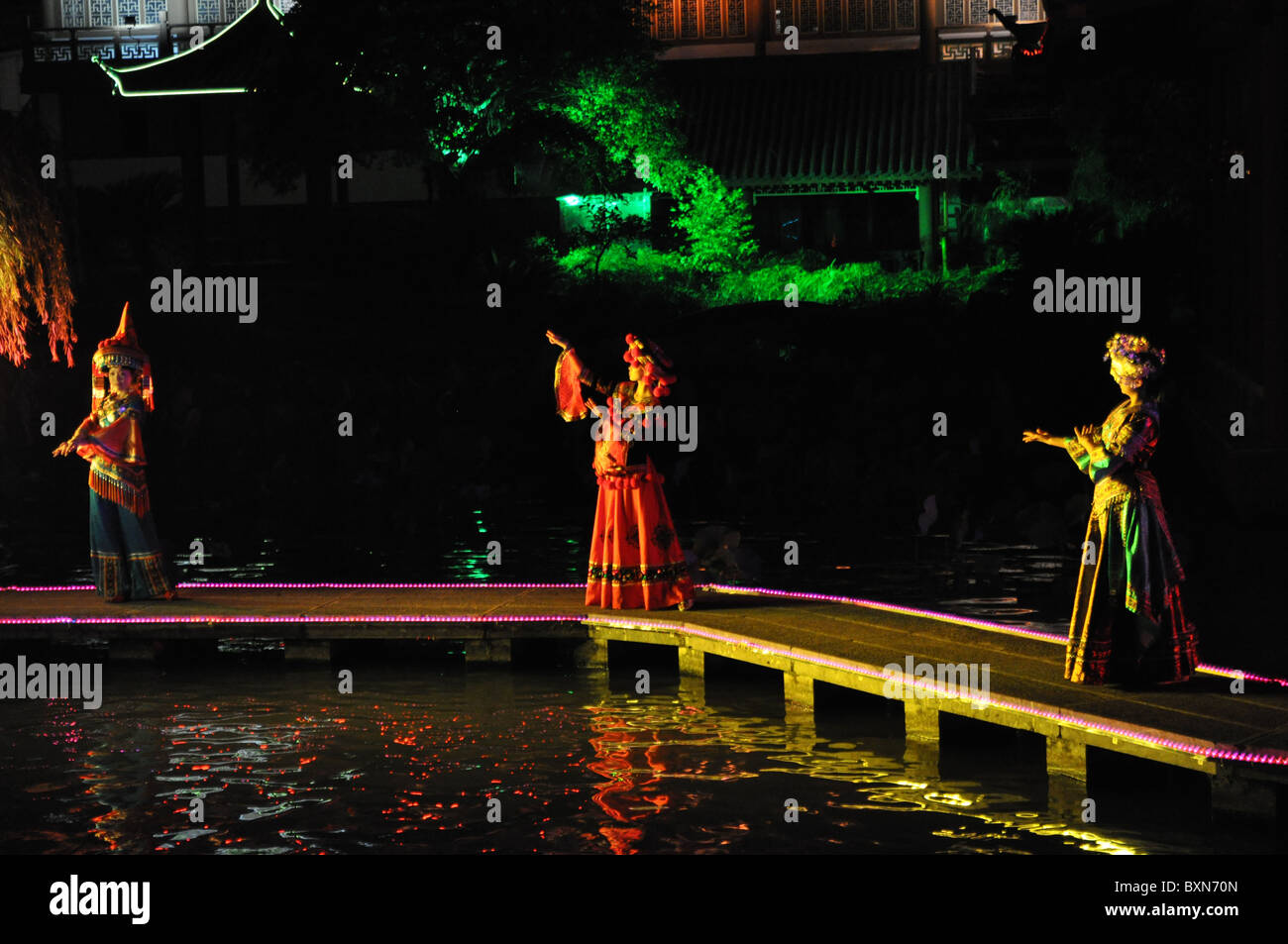 3 ballerini eseguono nella notte con grande illuminazione colorata Foto Stock