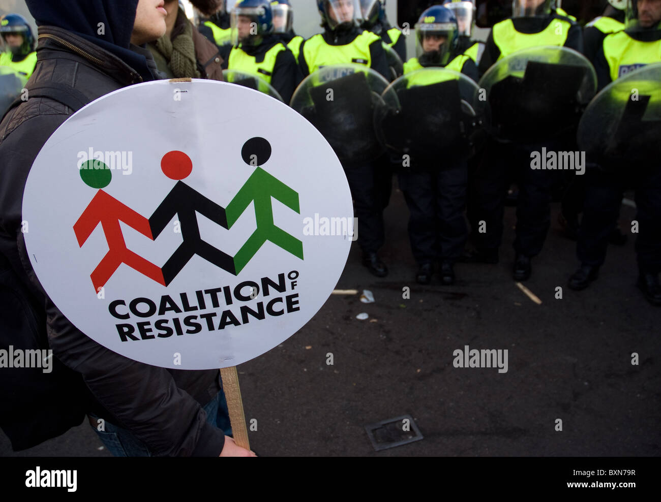 Un manifestante detiene una coalizione di targhetta di resistenza mentre riot cordone di polizia europeo Foto Stock