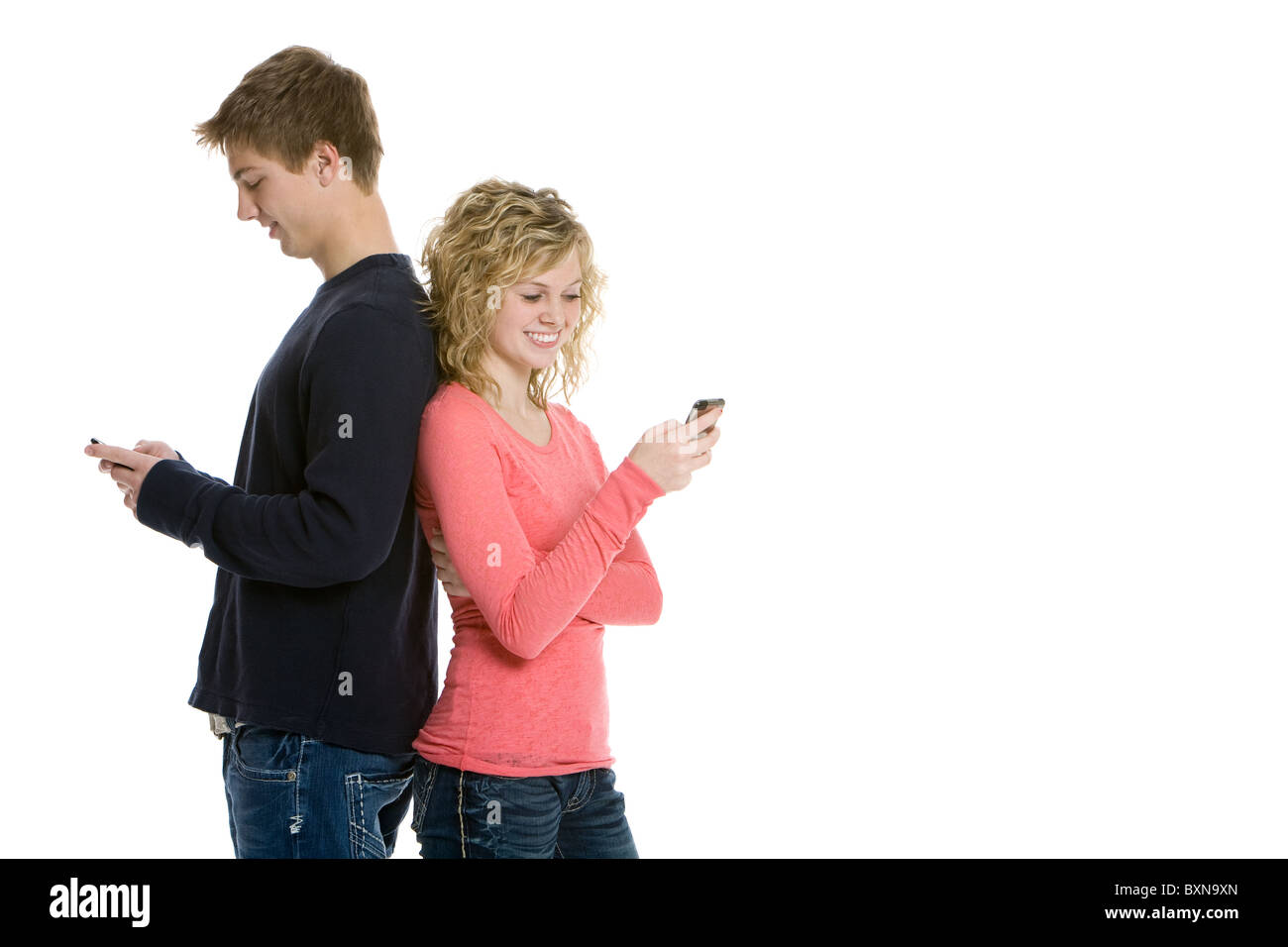 Attraente giovane adolescente in piedi di schiena in studio utilizzando i telefoni cellulari Foto Stock